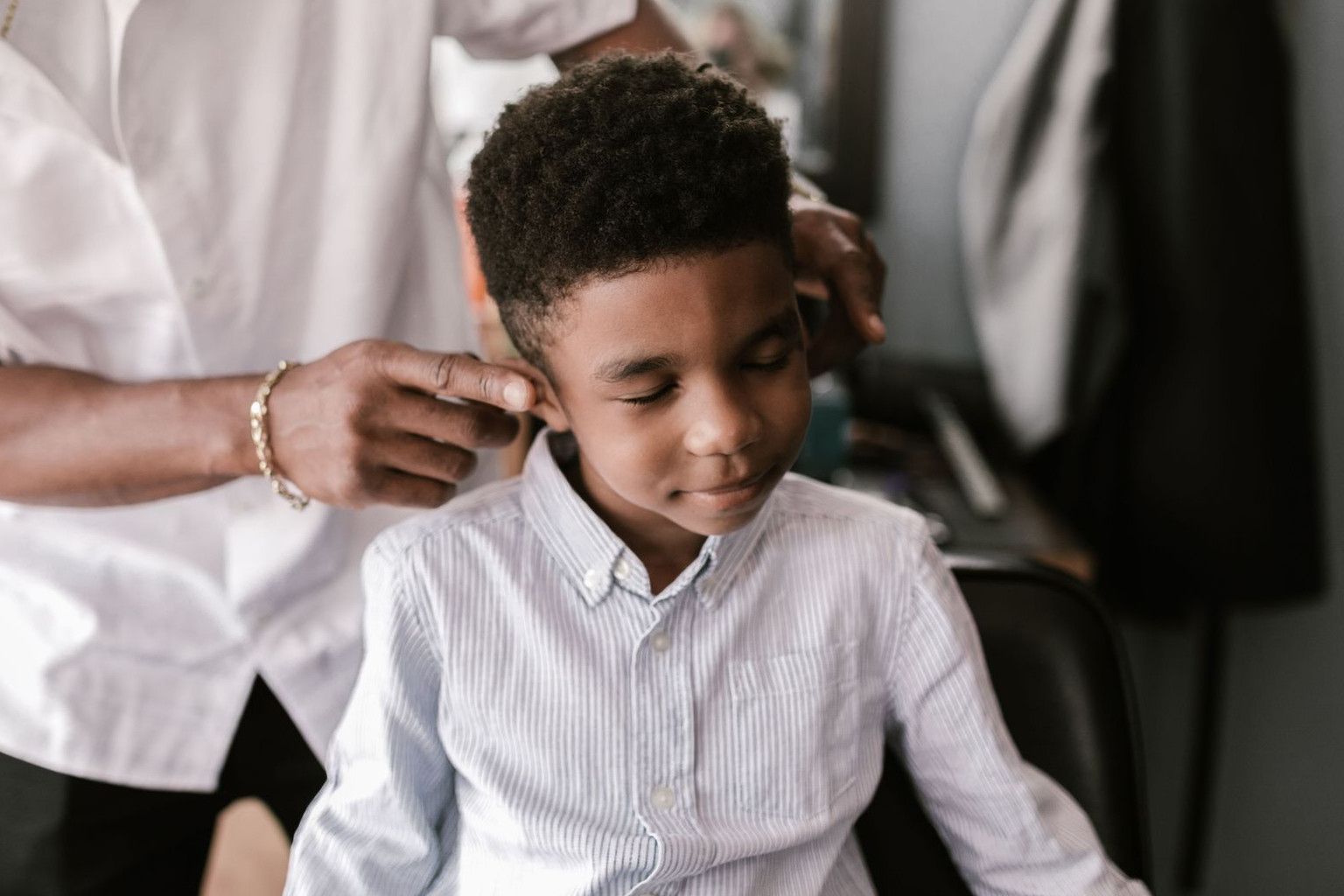 A young boy receiving a haircut from a barber in a salon setting.